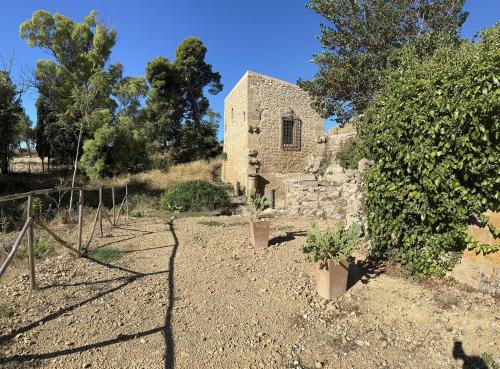 an old stone building with plants in a yard at Feudo Rosso di Cerami in Enna