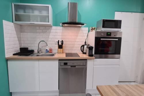 una pequeña cocina con fregadero y microondas en Appartement cosy Champagnole en Champagnole