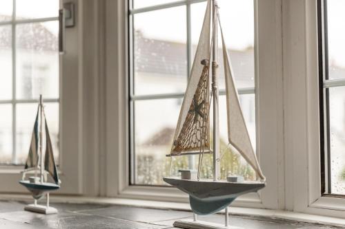 two miniature sailboats on display in a room with windows at Hebaska~Watergate Bay~3 Bedroom in Porth