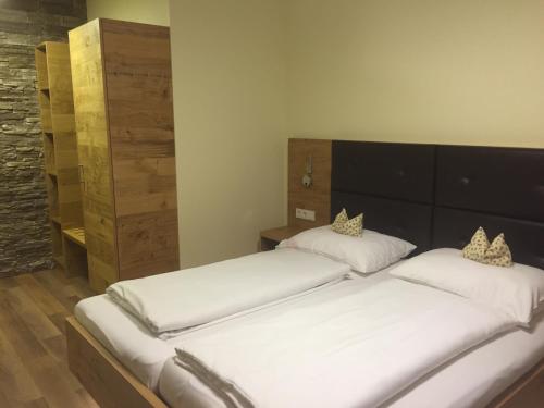 2 bedden in een kamer met witte lakens bij Schnepfenhof in Jois
