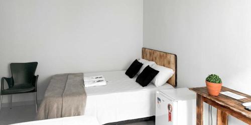 a bedroom with a white bed with a green chair at Hotel Rosa Viva in Barretos