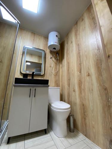 a bathroom with a toilet and a tv on the wall at Panorama Glamping in Saty