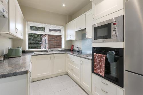 a kitchen with white cabinets and a stove top oven at Home from Home 4 Bed - Ideal for Workers & Great for Groups, FREE Parking, Spacious, Pet Friendly Netflix in Kimberworth