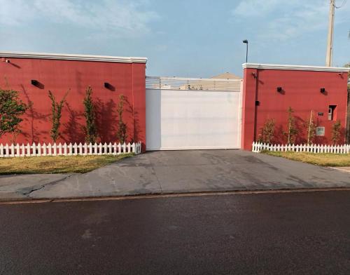 a red building with a white gate and a driveway at Hotel Rosa Viva in Barretos