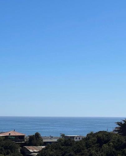 a view of the ocean with buildings and trees at Cabañas Luz de Luna, Playa Curanipe in Curanipe