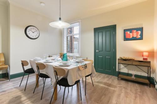 a dining room with a table with chairs and a clock at Home from Home 4 Bed - Ideal for Workers & Great for Groups, FREE Parking, Spacious, Pet Friendly Netflix in Kimberworth