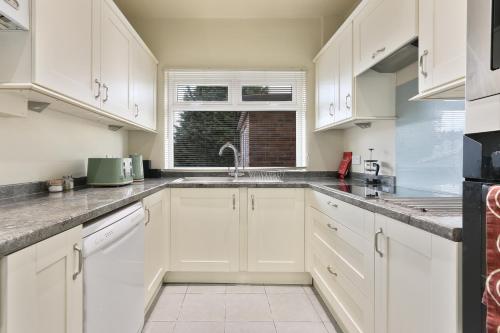 a white kitchen with white cabinets and a window at Home from Home 4 Bed - Ideal for Workers & Great for Groups, FREE Parking, Spacious, Pet Friendly Netflix in Kimberworth