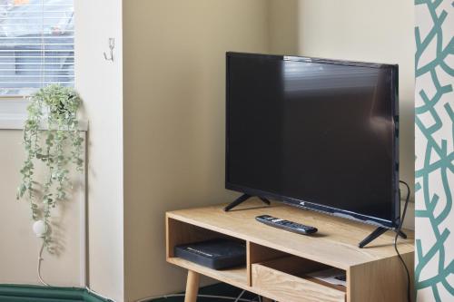 a television on a wooden stand with a remote control at Home from Home 4 Bed - Ideal for Workers & Great for Groups, FREE Parking, Spacious, Pet Friendly Netflix in Kimberworth