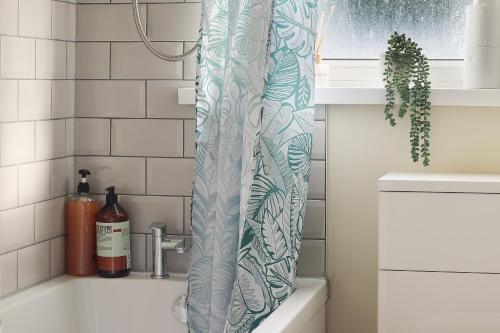 a shower curtain in a bathroom next to a sink at Home from Home 4 Bed - Ideal for Workers & Great for Groups, FREE Parking, Spacious, Pet Friendly Netflix in Kimberworth