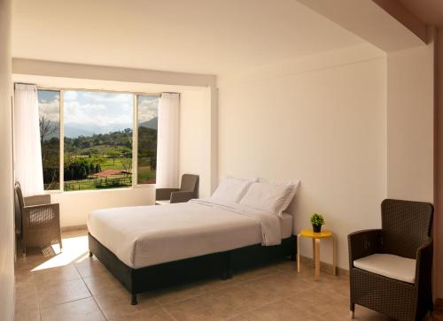a bedroom with a bed and a window and a chair at Apartamento Campestre en Condominio in Fusagasuga