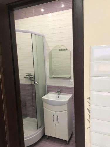 uma casa de banho com um lavatório, um chuveiro e um espelho. em Хостел Мрія em Uman