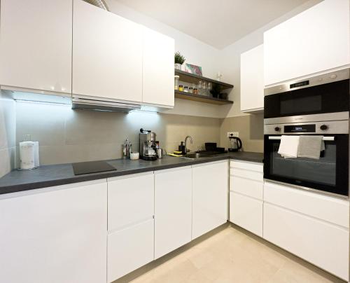 - une cuisine blanche avec des armoires blanches et des appareils noirs dans l'établissement Belgrade Riverfront Fortress Apartment, à Belgrade