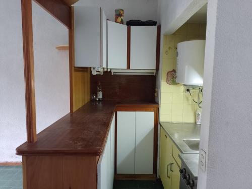 a small kitchen with white cabinets and a sink at Allá en el sur in Ezeiza