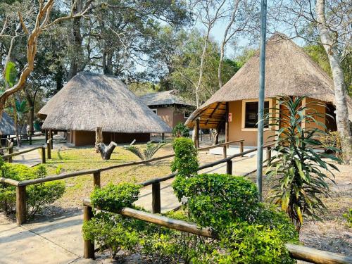 two huts with thatched roofs and a fence at THE GALAXY FOREST LODGE in Manguzi