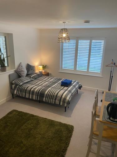 a bedroom with a bed and a table and windows at Very large double room with corner sofa and Sky TV in Newhaven