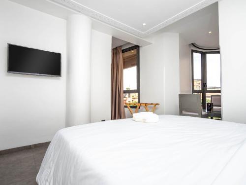 une chambre blanche avec un lit et une télévision à écran plat dans l'établissement Fashion Boutique Hotel, à Marrakech
