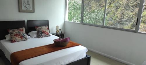 a bedroom with a bed and two windows at Ecusuites Puerto Santa Ana - River Junto a Hotel Wyndham in Guayaquil