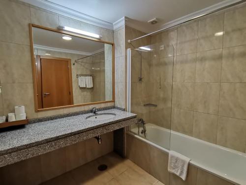 La salle de bains est pourvue d'un lavabo, d'une baignoire et d'un miroir. dans l'établissement Hotel Quinta dos Cedros, à Celorico da Beira