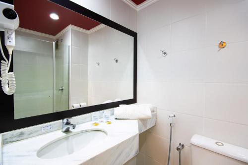 a bathroom with a sink and a large mirror at Hotel Dan Inn São Carlos By Nacional Inn in São Carlos