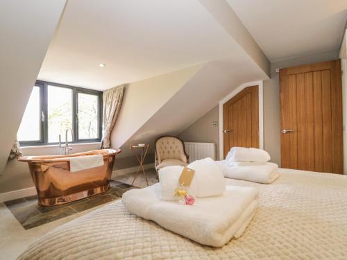 - une chambre avec une baignoire et un lit avec une chaise dans l'établissement Tarn End Cottages 12, à Brampton
