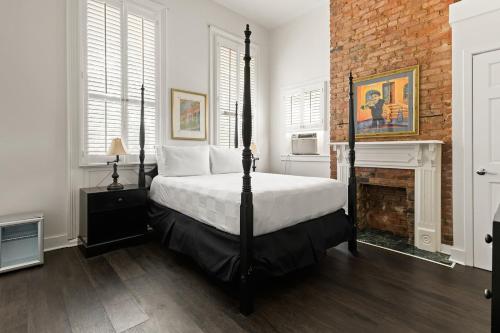a bedroom with a bed and a brick wall at Historic Streetcar Inn in New Orleans