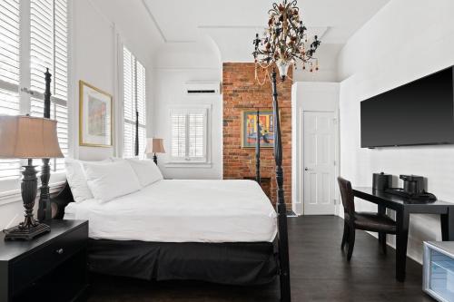 a bedroom with a bed and a desk and a television at Historic Streetcar Inn in New Orleans