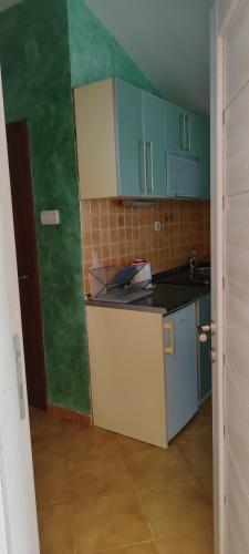 a small kitchen with blue cabinets and a green wall at Sea and Sunshine in Tivat