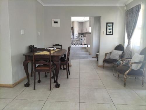 a dining room with a wooden table and chairs at AKANI Guesthouse Cosmo city in Roodepoort