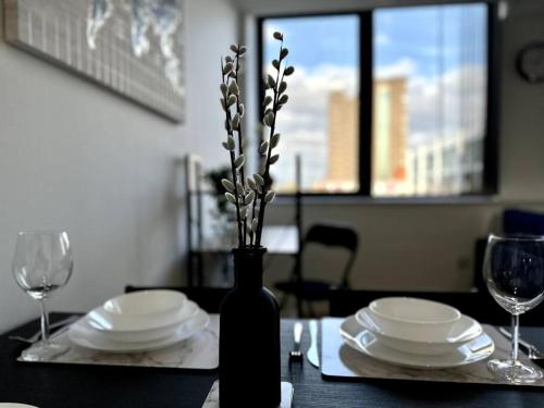 a table with plates and a vase with flowers in it at Luxury 1 Bedroom Apartment in Old Trafford in Manchester