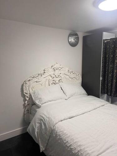 a bedroom with a white bed with a headboard at Cosy and warm studio apartment in Bexleyheath in Belvedere