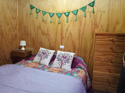 - une chambre avec un lit avec deux oreillers et une bannière dans l'établissement Cabañas aikus, à Mantilhue
