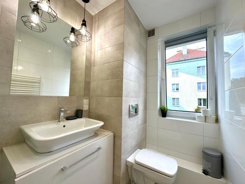 een badkamer met een wastafel, een toilet en een raam bij MMRent Bubble Room in Gdańsk