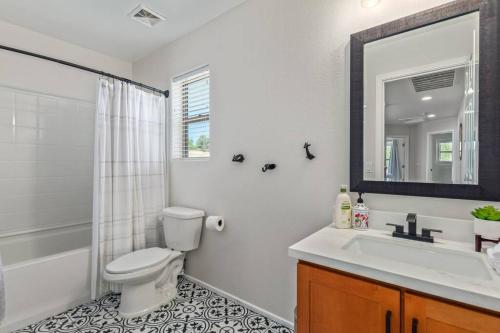 a bathroom with a toilet and a sink and a mirror at Sunny Arizona Getaway Your Home Under theDesertSun in Mesa