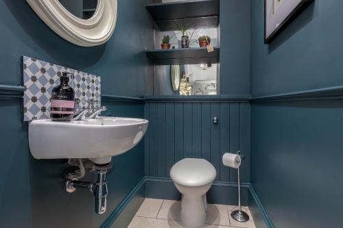 een badkamer met blauwe muren, een wastafel en een toilet bij Stylish Victorian Apartment's close to the Botanical gardens, Free parking! in Edinburgh