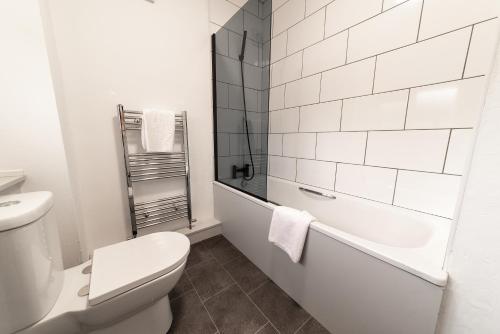 a white bathroom with a toilet and a bath tub at Jesmond Square in Hartlepool