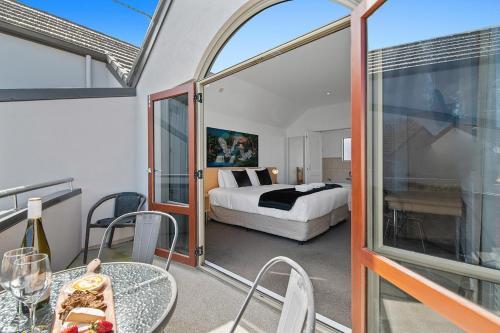 a bedroom with a bed and a balcony with a table at Taupo Central Apartment in Taupo