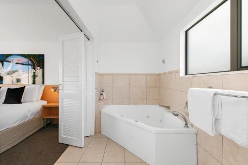 a white bathroom with a tub and a bed at Taupo Central Apartment in Taupo