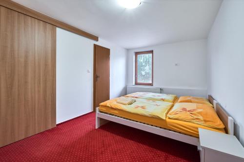 1 dormitorio con 1 cama y alfombra roja en Apartmány Kateřina, en Říčany