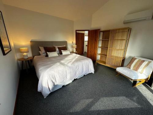 a bedroom with a large bed and a chair at Woolshed 17 - Self Catering Accommodation in Havelock North