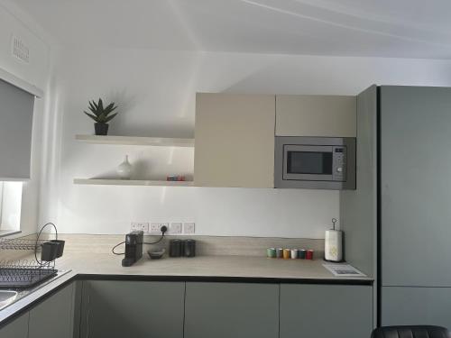 a kitchen with white cabinets and a microwave at Sliema 2 Bedroom Penthouse in Sliema