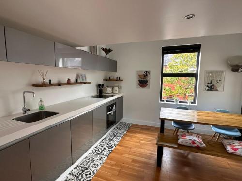a kitchen with a sink and a wooden table at Luxury Townhouse, Manchester Sleeps 6 in Manchester