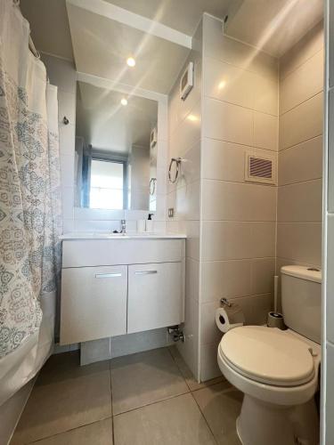 a white bathroom with a toilet and a sink at Apartamento General Mackenna B&E in Santiago