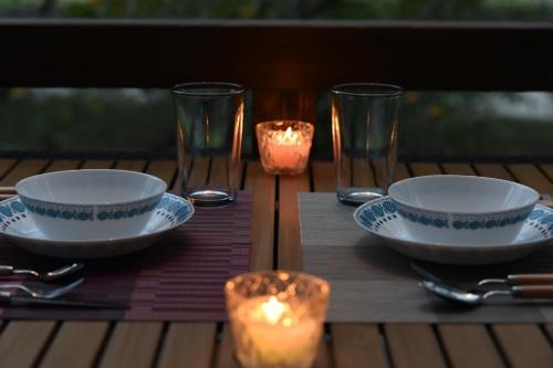a table with two bowls and two glasses and candles at Angler's Base SHIMOKITAYAMA Fishing Lodge - Vacation STAY 73805v in Kami-ikehara