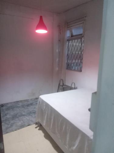 een witte kamer met een bed en een rood licht bij Casa de Portas para Frente in Vitória