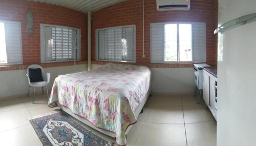 a bedroom with a bed and a kitchen with windows at Quarto aconchegante Barão Geraldo in Campinas