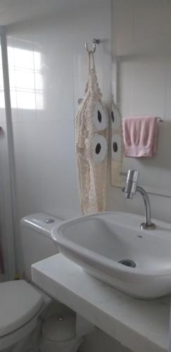 La salle de bains blanche est pourvue d'un lavabo et de toilettes. dans l'établissement Quarto aconchegante Barão Geraldo, à Campinas