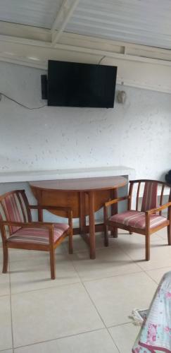 a table and two chairs with a television on a wall at Quarto aconchegante Barão Geraldo in Campinas
