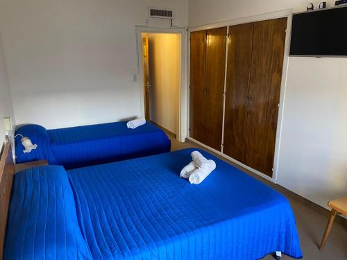 a room with two blue beds and a television at Nueva Hostería Rio Colorado Necochea in Necochea