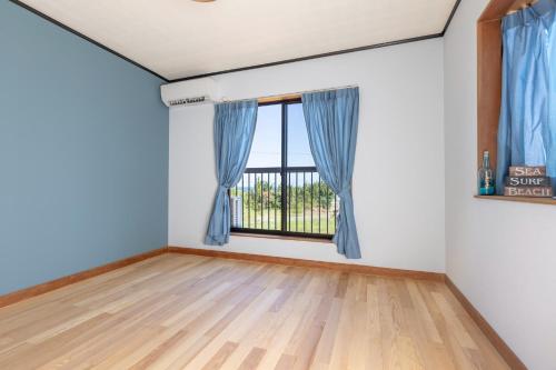 Cette chambre vide dispose d'une fenêtre avec des rideaux bleus. dans l'établissement ocean view mint - Vacation STAY 62937v, à Minamiboso