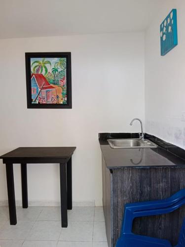 a kitchen with a sink and a table and a picture at Sunny Beach Apartments in San Andrés